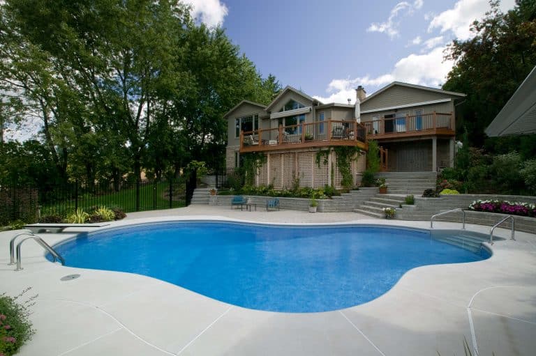 beautiful inground pool on beautifully landscaped yard with fence