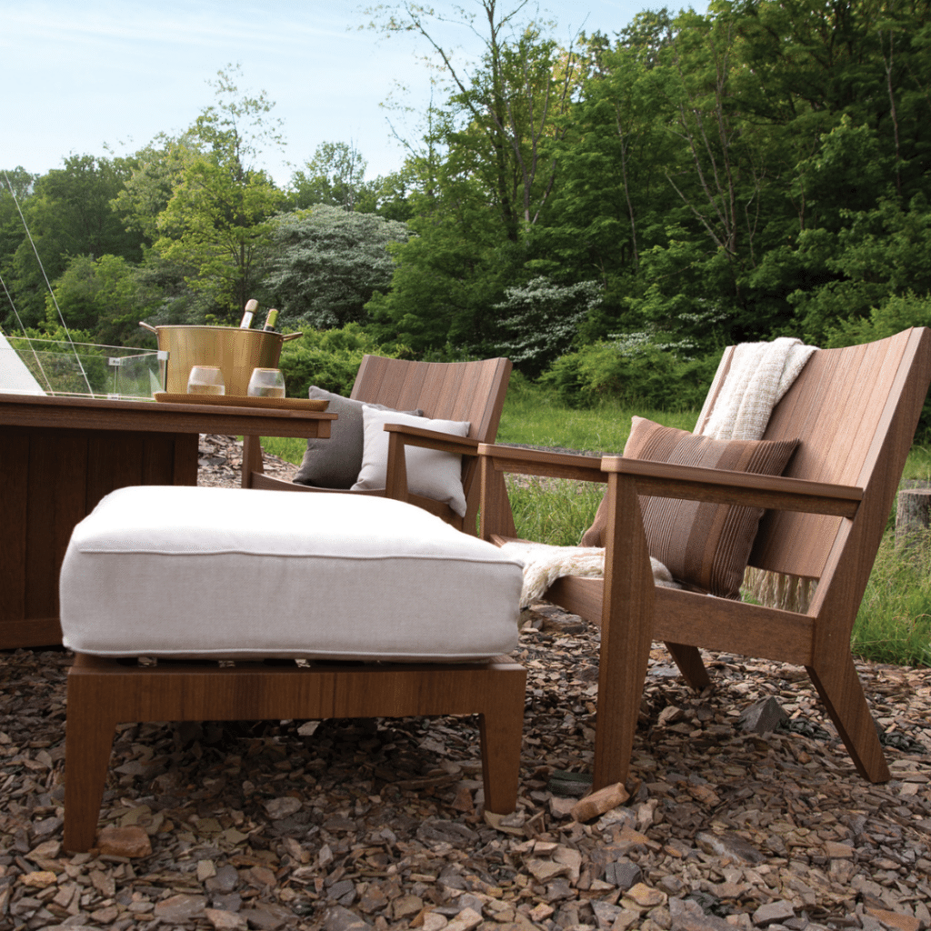 Berlin gardens Mayhew Chat chair in antique Mahogany with white cushions and accent pillows on a gravel surface